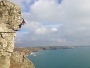 Jonny after the crux of West Wing, Porthleven and the Lizard stretching out in the background