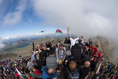 Sir Chris Bonnington holds the Olympic Torch Aloft England and Wales on the Summit of Snowdon.  © Mark Reeves