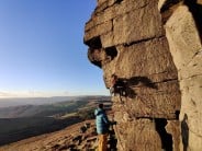 Rab athlete, Hannah Smith on her 2nd ever trad lead during a January Stanage sunset.